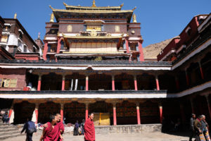 Drei Mönche laufen lachend über den Hof vor dem Haupthaus des Kloster Tashilunpo in Tibet.