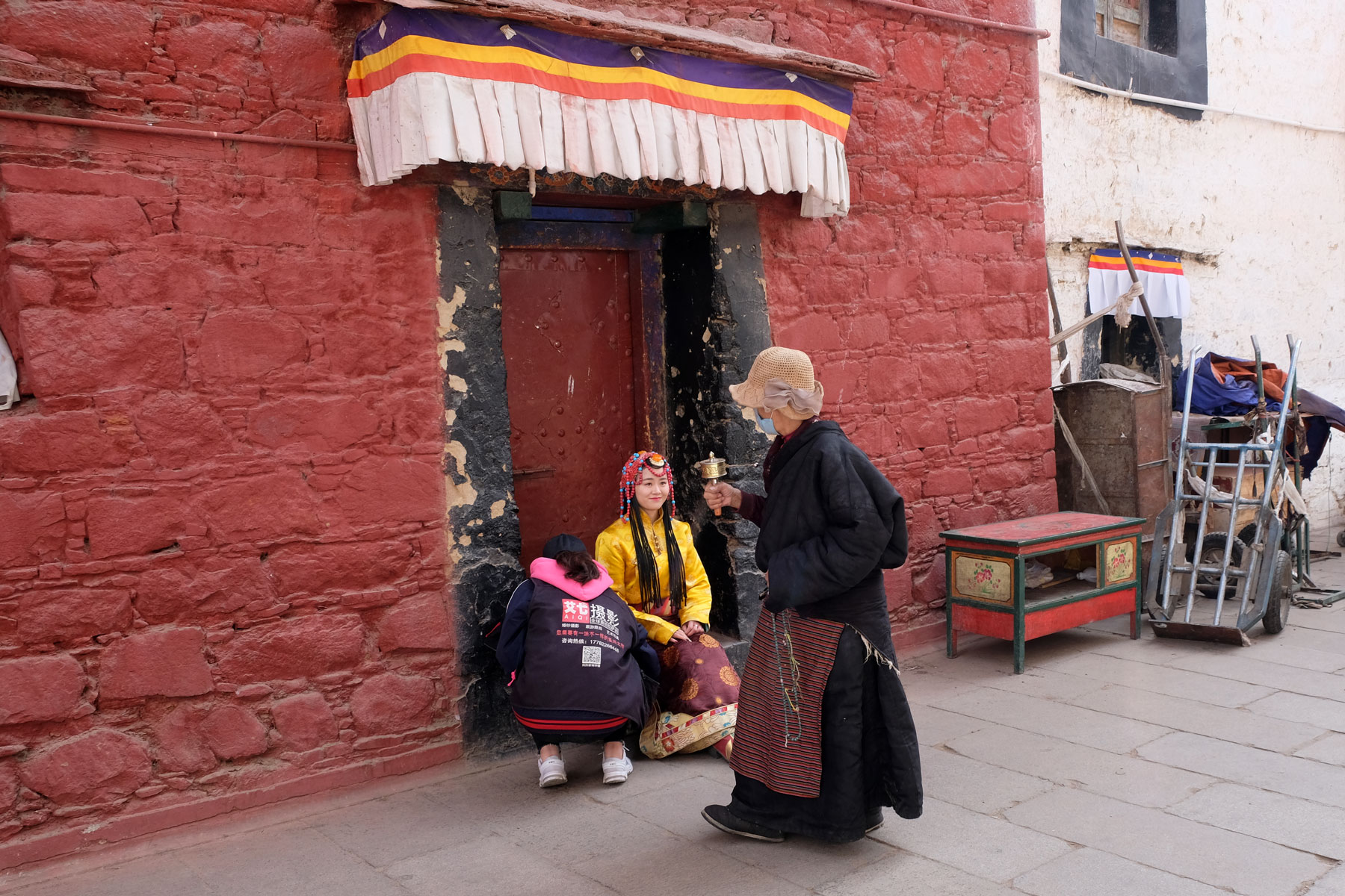 Eine Tibeterin läuft an einem Fotoshooting vorbei, bei dem sich eine Han-Chinesin in tibetischer Kleidung fotografieren lässt.