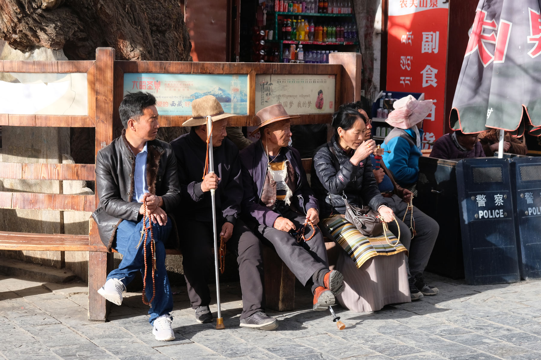 Eine Gruppe Tibeter sitzt am Rande des Barkhors in Lhasa in Tibet zusammen.