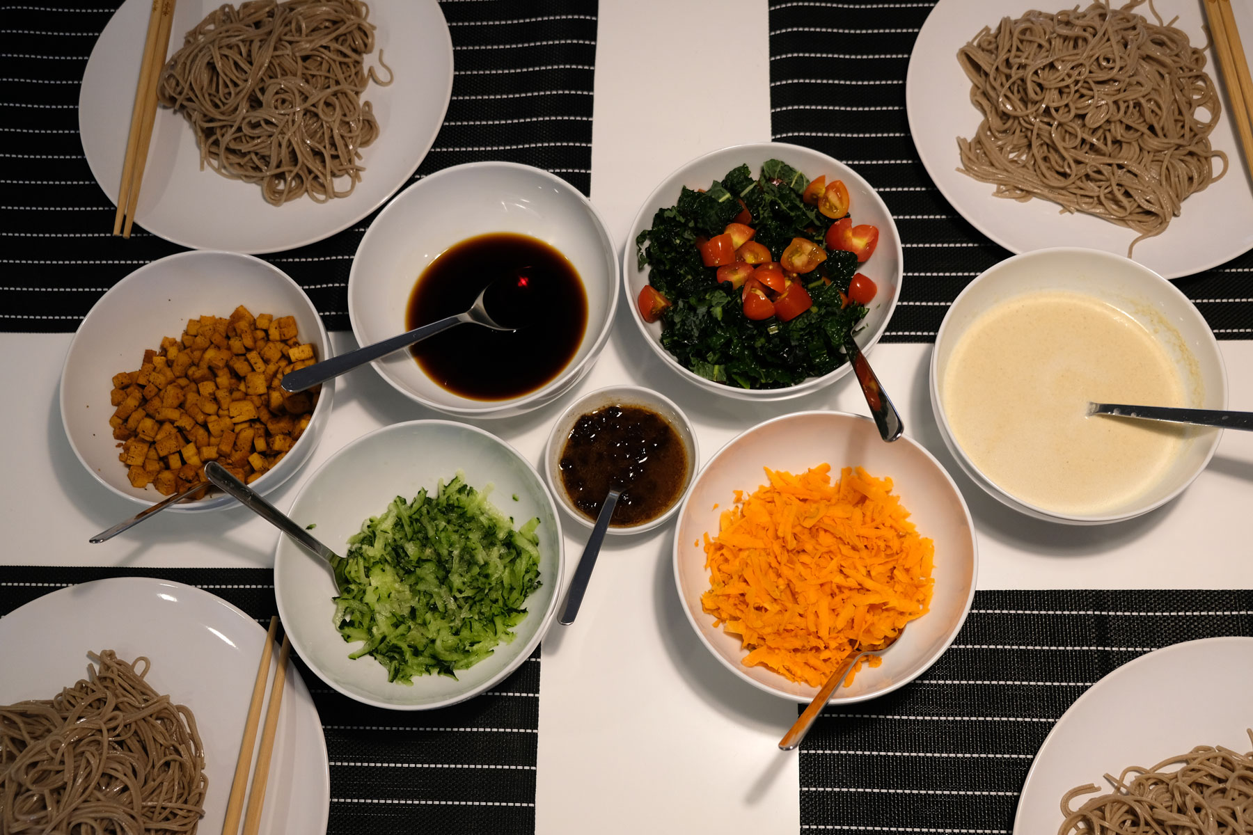 Auf dem Tisch stehen viele Schalen mit veganem Bio-Essen und Spaghetti.