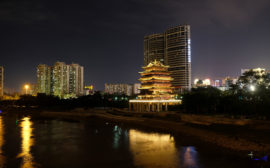 Am Fluss in Nanning leuchtet ein Tempel in der Nacht, neben ihm die Hochhäuser.