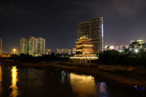 Am Fluss in Nanning leuchtet ein Tempel in der Nacht, neben ihm die Hochhäuser.