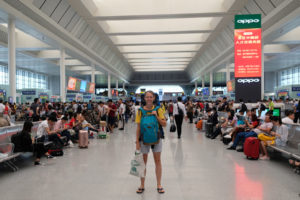 Leo steht mit ihrem Gepäck in der Halle des Bahnhofs Nanning in China.