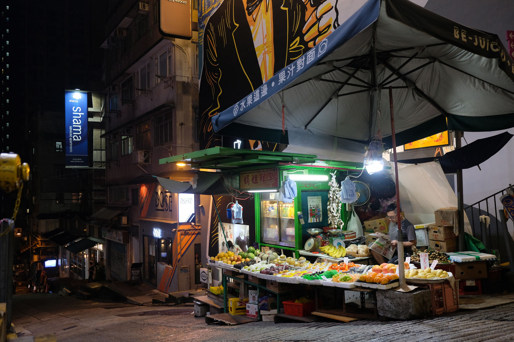 Ein beleuchteter Stand auf der Straße verkauft in der Dunkelheit Obst und Gemüse in Hongkong.