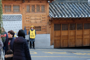 Eine Aufpasserin trägt eine Weste mit der Aufschrift "Please be quite!" im Bukchon Hanok Village in Seoul, Südkorea.