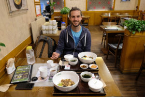 Sebastian sitzt in Südkorea im Restaurant und isst Bibimbap.