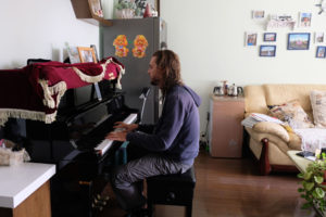 Sebastian spielt Klavier im Wohnzimmer von Sunny und Terry.