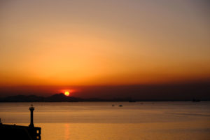 Über dem Hafen von Qingdao in China geht die Sonne unter.