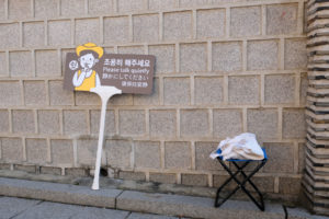 Ein Schild mit der Aufschrift "bitte leise reden" lehnt an einer Wand im Bukchon Hanok Village in Südkorea.