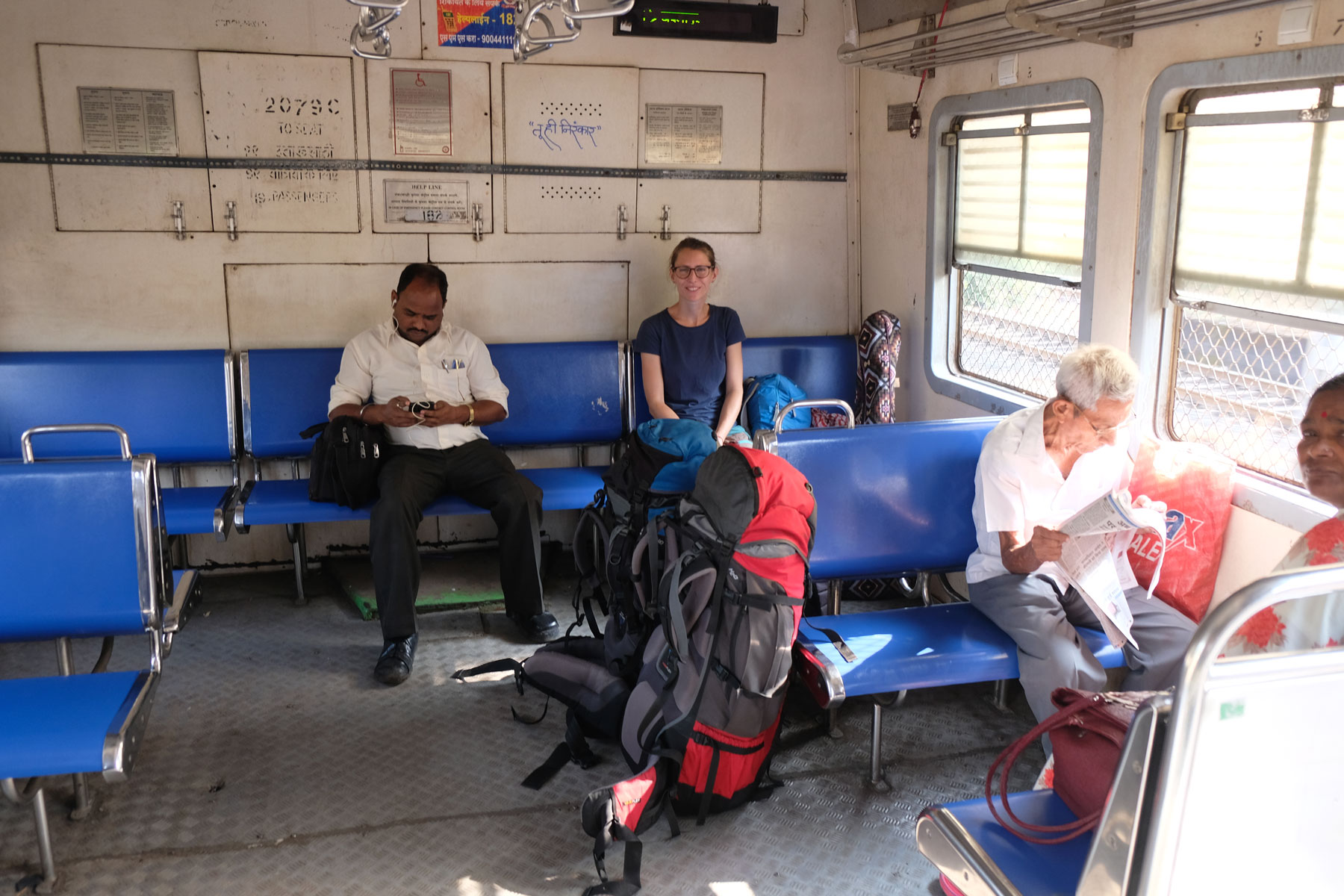 Leo sitzt mit anderen Fahrgästen in einem Regionalzug in Mumbai.
