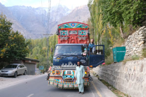Ein Mann steht vor einem reich verzierten Lastwagen in Pakistan.