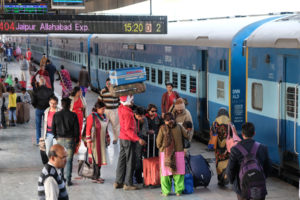 Menschen und ein Zug im Bahnhof von Jaipur.