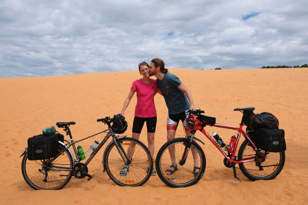 Leo und Sebastian stehen mit ihren Fahrrädern auf einer Sanddüne in Vietnam.