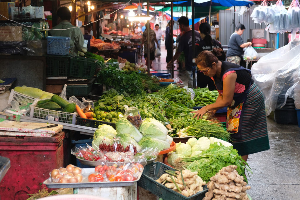 Eine thailändische Frau kauft Gemüse auf einem Markt in Bangkok.