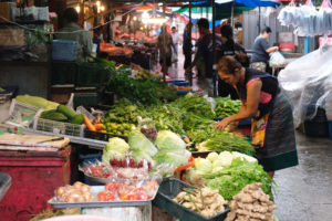 Eine thailändische Frau kauft Gemüse auf einem Markt in Bangkok.